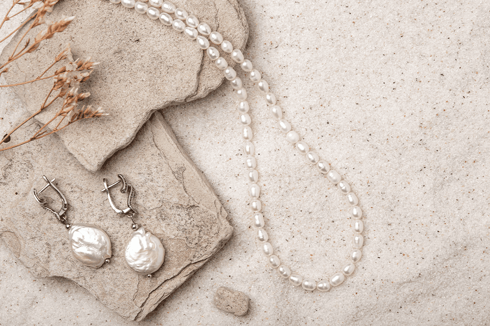 Pearl necklace and earrings on the sand 