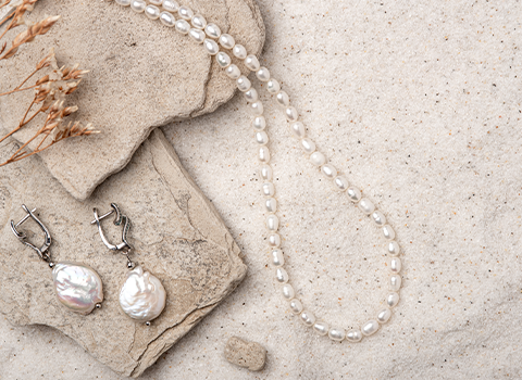 Pearl necklace and earrings on the sand 